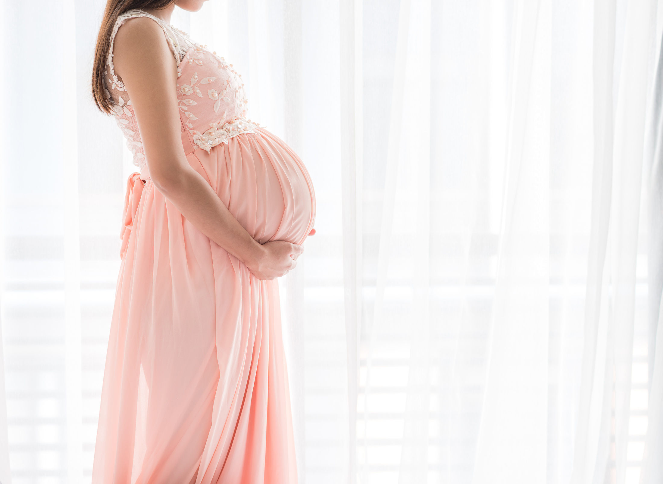 Pregnant Woman Wearing Pink Dress Standing by the Curtain